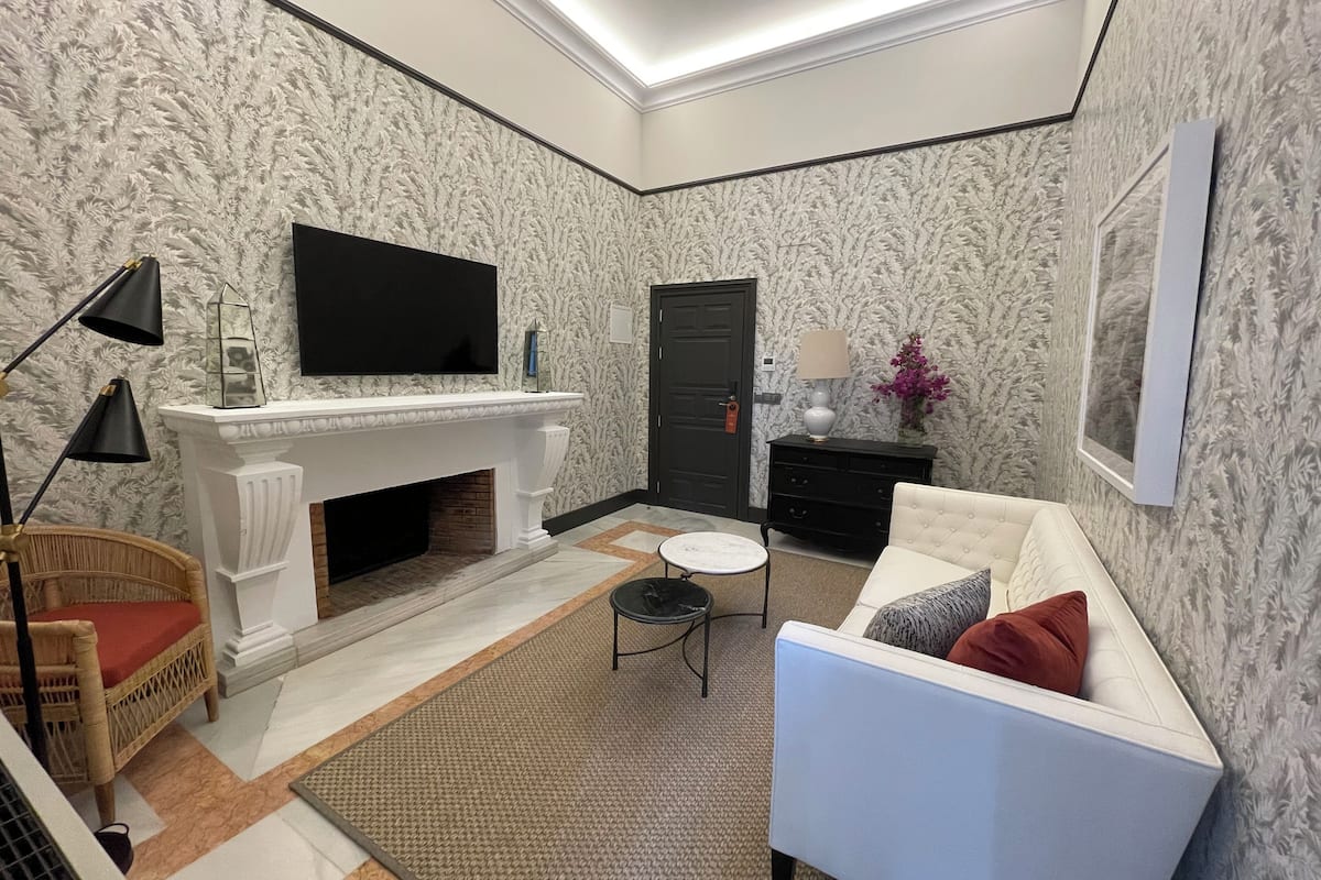 A modern living room with a fireplace, a flat-screen TV, a sofa, and a decorative lamp.