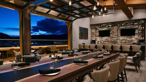 A bar area with a long wooden counter, wicker chairs, and a bar stocked with various bottles. - Homewood Suites by Hilton Dillon (Dillon)