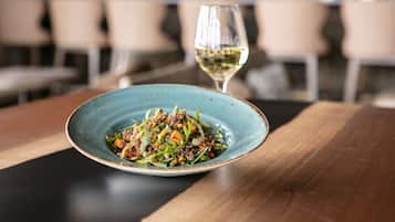A plate of food on a wooden table with a glass of white wine.