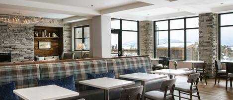A modern dining area with a stone wall, a bench, and tables.