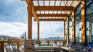 A covered outdoor seating area with a pool, chairs, and a view of snow-capped mountains. - Homewood Suites by Hilton Dillon (Dillon)
