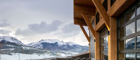 Un restaurante con terraza al aire libre y vistas a montañas nevadas.