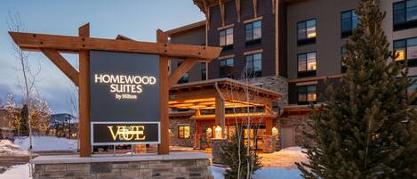A hotel entrance with a sign for Homewood Suites by Hilton and a VOTE sign.