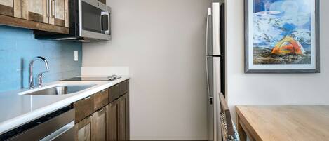 Cocina moderna con armarios de madera, electrodomésticos de acero inoxidable, un lavamanos doble y una obra de arte enmarcada en la pared.