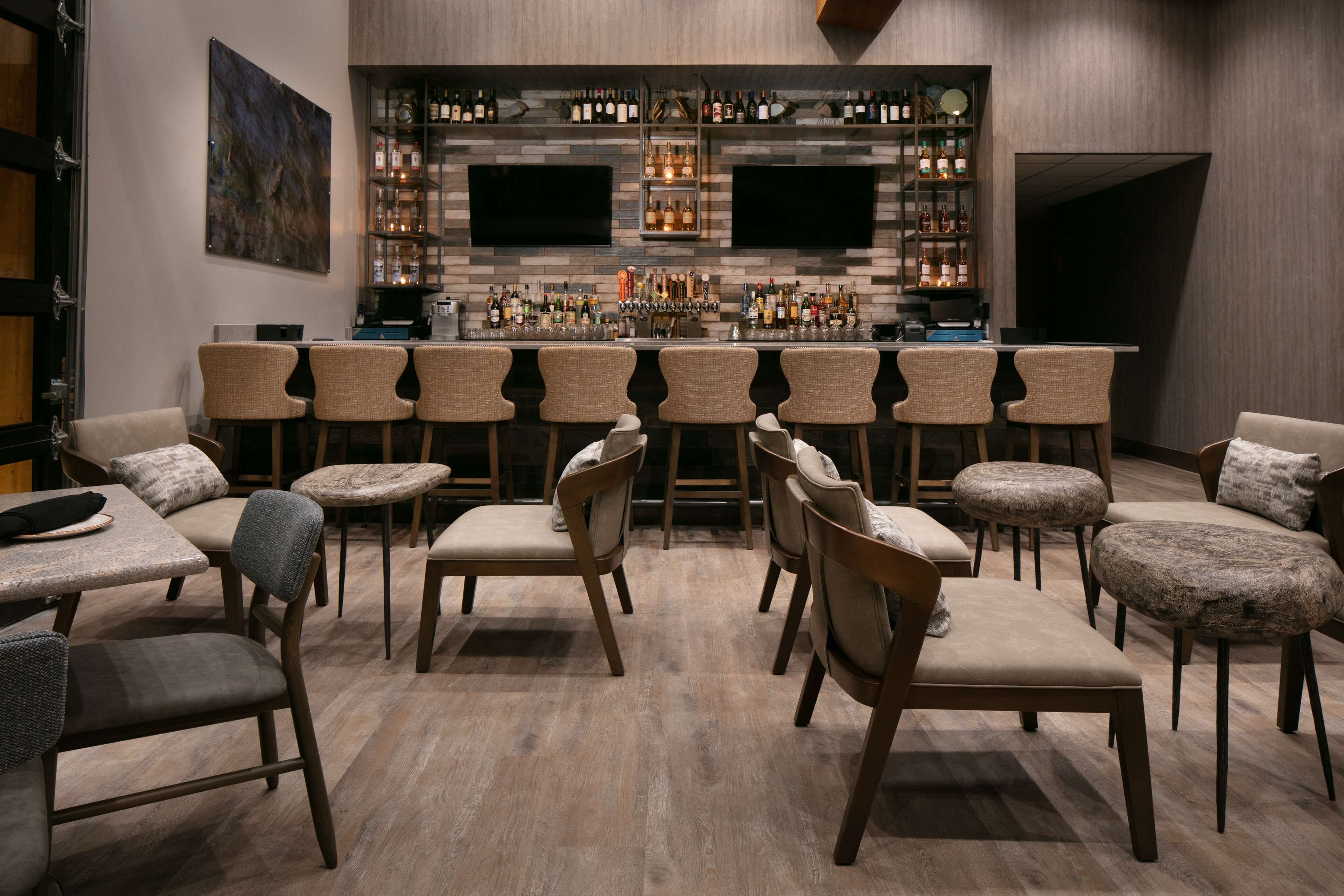 A bar area with multiple seating options, including bar stools and chairs, and a well-stocked bar counter.