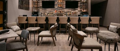 A bar area with multiple seating options, including bar stools and chairs, and a well-stocked bar counter.