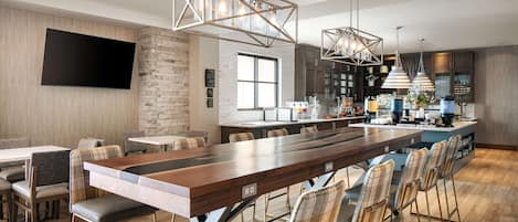 A modern kitchen with a long wooden bar, built-in appliances, and pendant lighting.