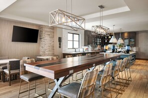 A modern kitchen with a long wooden bar, built-in appliances, and pendant lighting. - Homewood Suites by Hilton Dillon (Dillon)