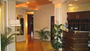 A reception area with a reception desk, a reception counter, and potted plants. - Imperial Hotel (Primorsko)
