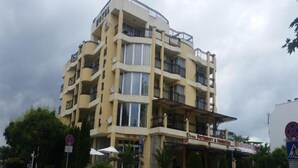 A multi-story hotel with balconies, a storefront for a perfumery and cosmetics shop, and a pedestrian crossing sign. - Imperial Hotel (Primorsko)