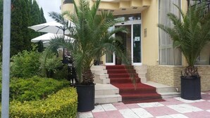 A hotel entrance with a red carpet, palm trees, and a checkered pavement. - Imperial Hotel (Primorsko)