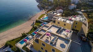 Eine Küstenwohngegend mit Strand, einer Reihe gelber Gebäude mit Dachpools und freiem Blick auf das Meer.