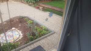 A garden with a mosaic tile design, a wooden fence, and a gravel path.