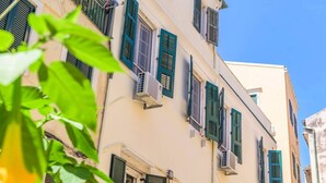 A building with multiple windows, some with shutters, and air conditioning units attached to the exterior. - Archontiko Contessina Angelika (Corfu)