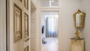 A hallway with a white door, a mirror with a gold frame, and a small table with a lamp. - Archontiko Contessina Angelika (Corfu)