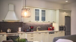 A modern kitchen with white cabinets, a stainless steel refrigerator, a coffee maker, and a sink. - Archontiko Contessina Angelika (Corfu)