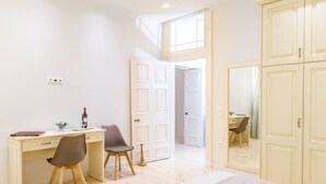 A bedroom with a bed, a desk with a chair, a wardrobe, and a door leading to another room. - Archontiko Contessina Angelika (Corfu)