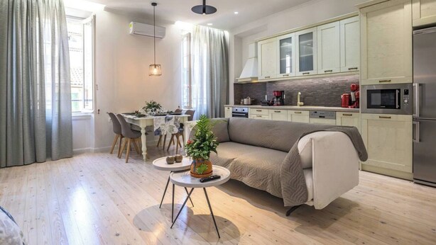 A modern kitchen with stainless steel appliances, a dining area with a table set for four, and a cozy living space with a sofa and a small side table. - Archontiko Contessina Angelika (Corfu)