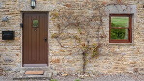 Un bâtiment en pierre avec une porte marron et une fenêtre.