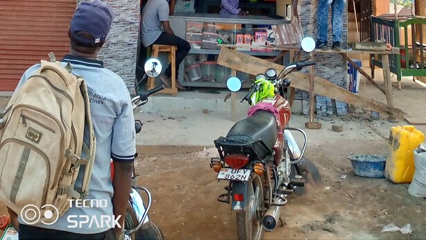 A multi-story building with a sign for a memorial house and a shop selling phones and accessories. - Compassionate Homestead (Kampala)