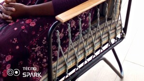 A person seated on a chair with a view of a residential area. - Compassionate Homestead (Kampala)