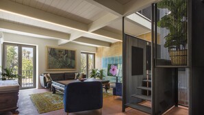 A spacious living area with a large sofa, a coffee table, and a TV. There is a staircase with a black railing and a large window with a view of trees. - Palermo Magic House (palermo)
