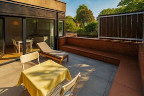 An outdoor patio with a table and chairs, a sun lounger, and a brick wall. - Mauerpark Mitte-Prenzl.Berg Penthouse, modern and authentic. 3 BR, 2 Bath (Berlin)