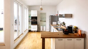 Eine moderne Küche mit einer Holzarbeitsplatte, eingebauten Geräten und Blick zum Garten.
