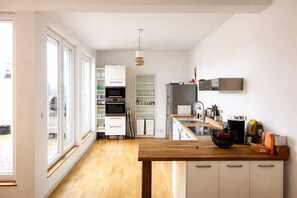 A modern kitchen with a wooden countertop, built-in appliances, and a view of the backyard. - Mauerpark Mitte-Prenzl.Berg Penthouse, modern and authentic. 3 BR, 2 Bath (Berlin)