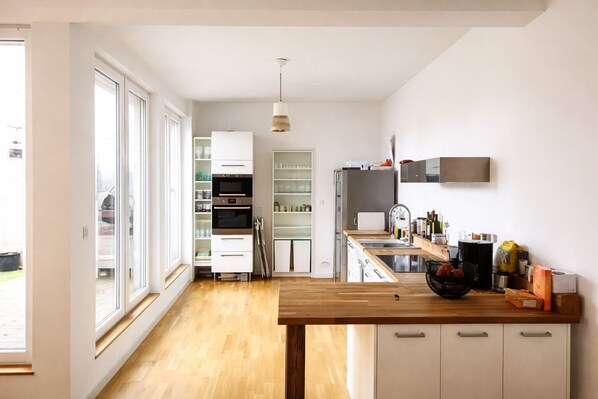 A modern kitchen with a wooden countertop, built-in appliances, and a view of the backyard.