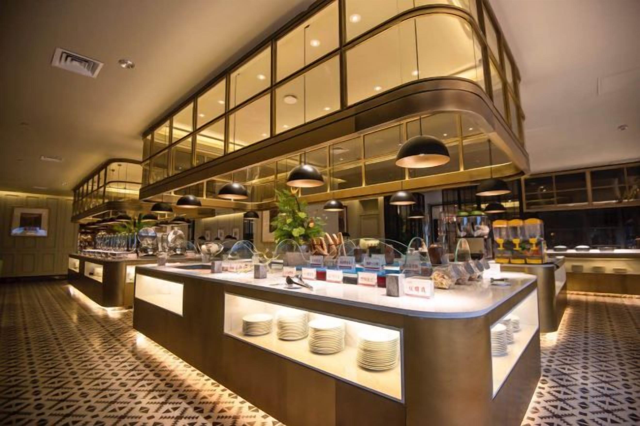 Un espace buffet doté d’un îlot central, d’un éclairage suspendu et d’un sol à motifs.