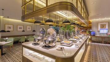 A hotel breakfast area with a buffet setup, including various food items and a coffee station.