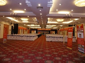 A hotel conference room with rows of tables, chairs, and banners. - Century Plaza Qidu Hotel (Zibo)
