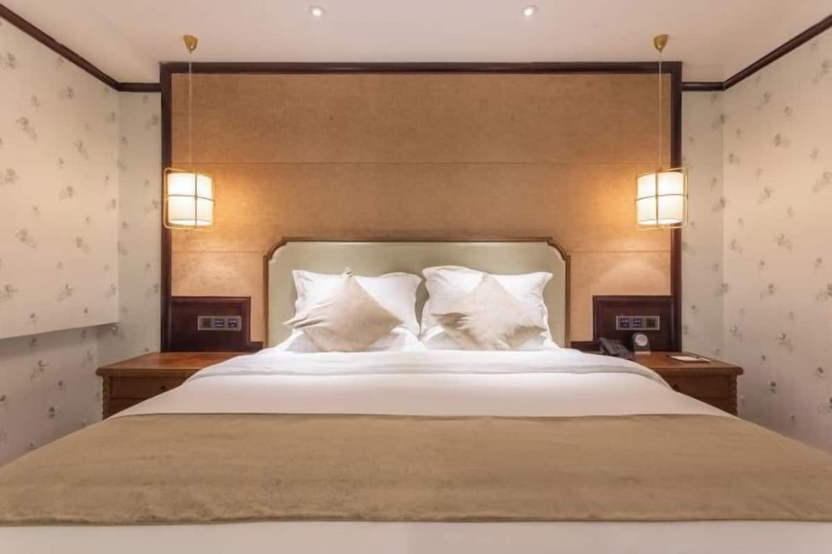 Een hotelkamer met een groot bed, twee nachtkastjes, een hoofdbord en twee wandlampen.