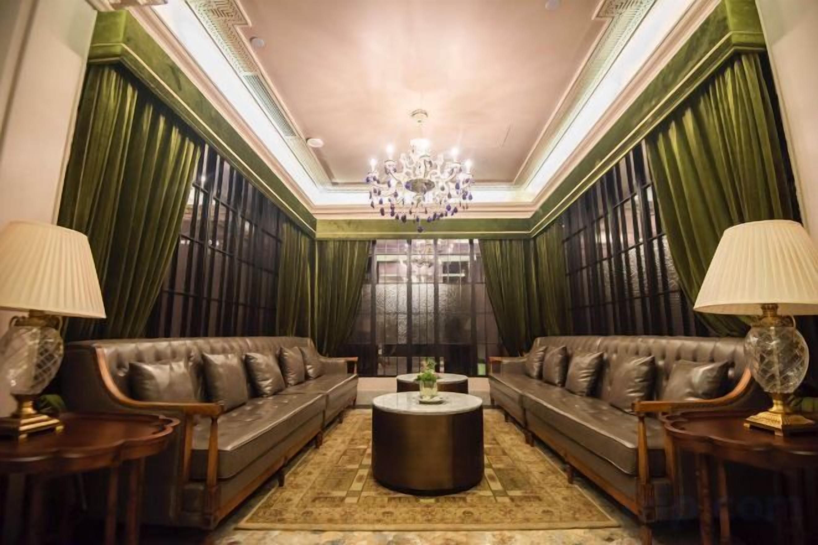 Ein Zimmer mit zwei Ledersofas, einem runden Couchtisch und Lampen auf Beistelltischen.