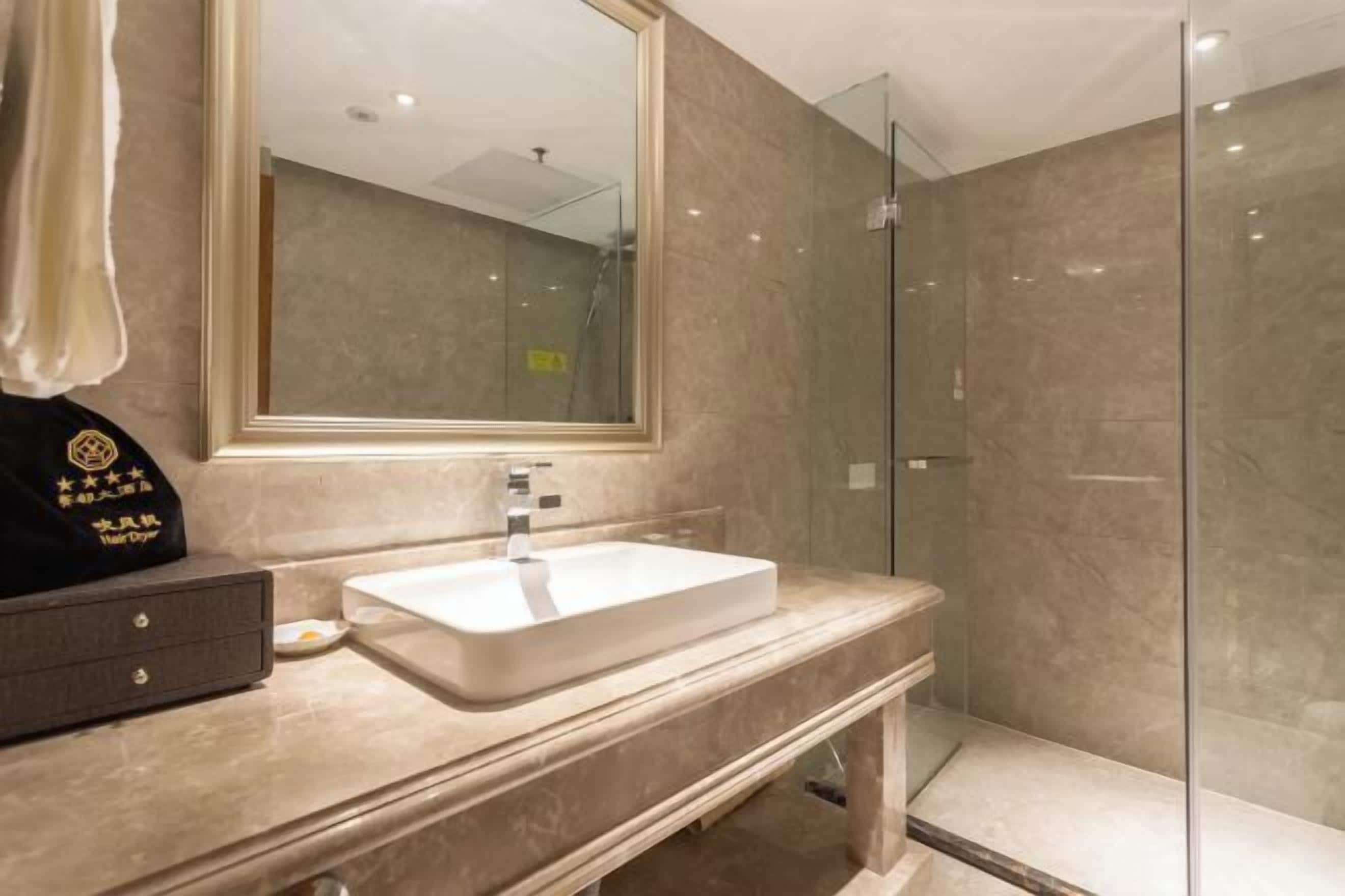 A modern bathroom with a large mirror, a white sink, and a glass shower enclosure.