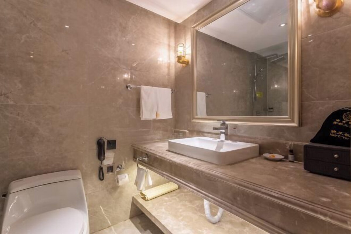 A modern bathroom with a large mirror, a white sink, and a toilet.