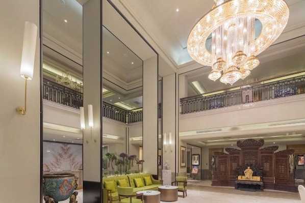 A spacious lobby with a chandelier, seating area, and a decorative wall. - Century Plaza Qidu Hotel (Zibo)