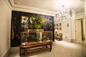 A lobby with a wooden console table, a chandelier, and a door leading to another room. - Century Plaza Qidu Hotel (Zibo)