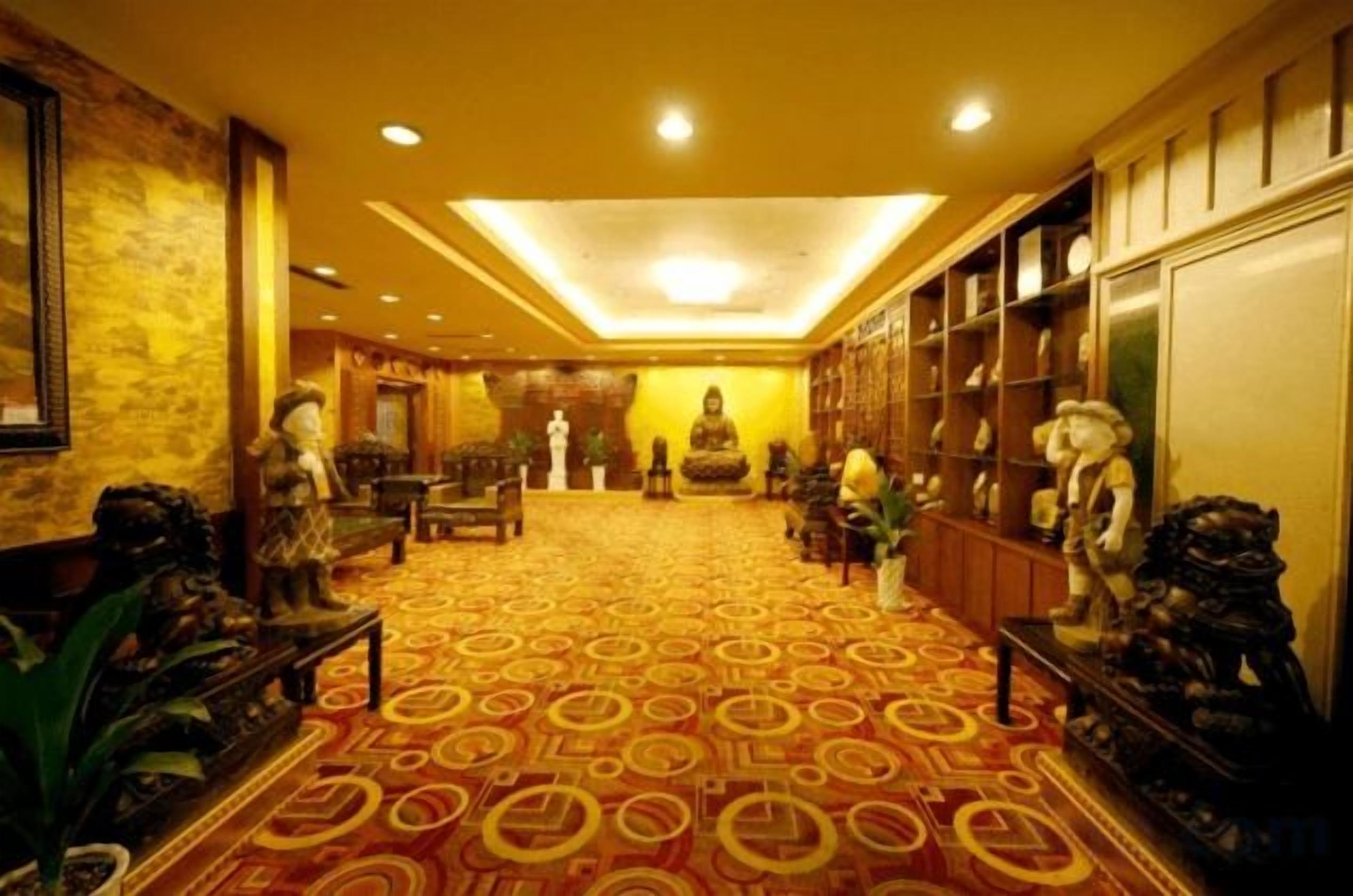 Una hall d'albergo con una moquette decorata, zone relax e statue ornamentali.
