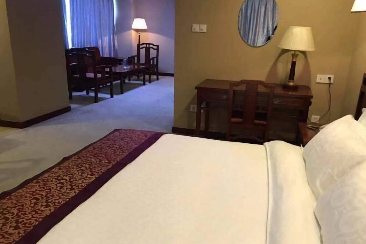 Een hotelkamer met een bed, een bureau, een stoel en een lamp.