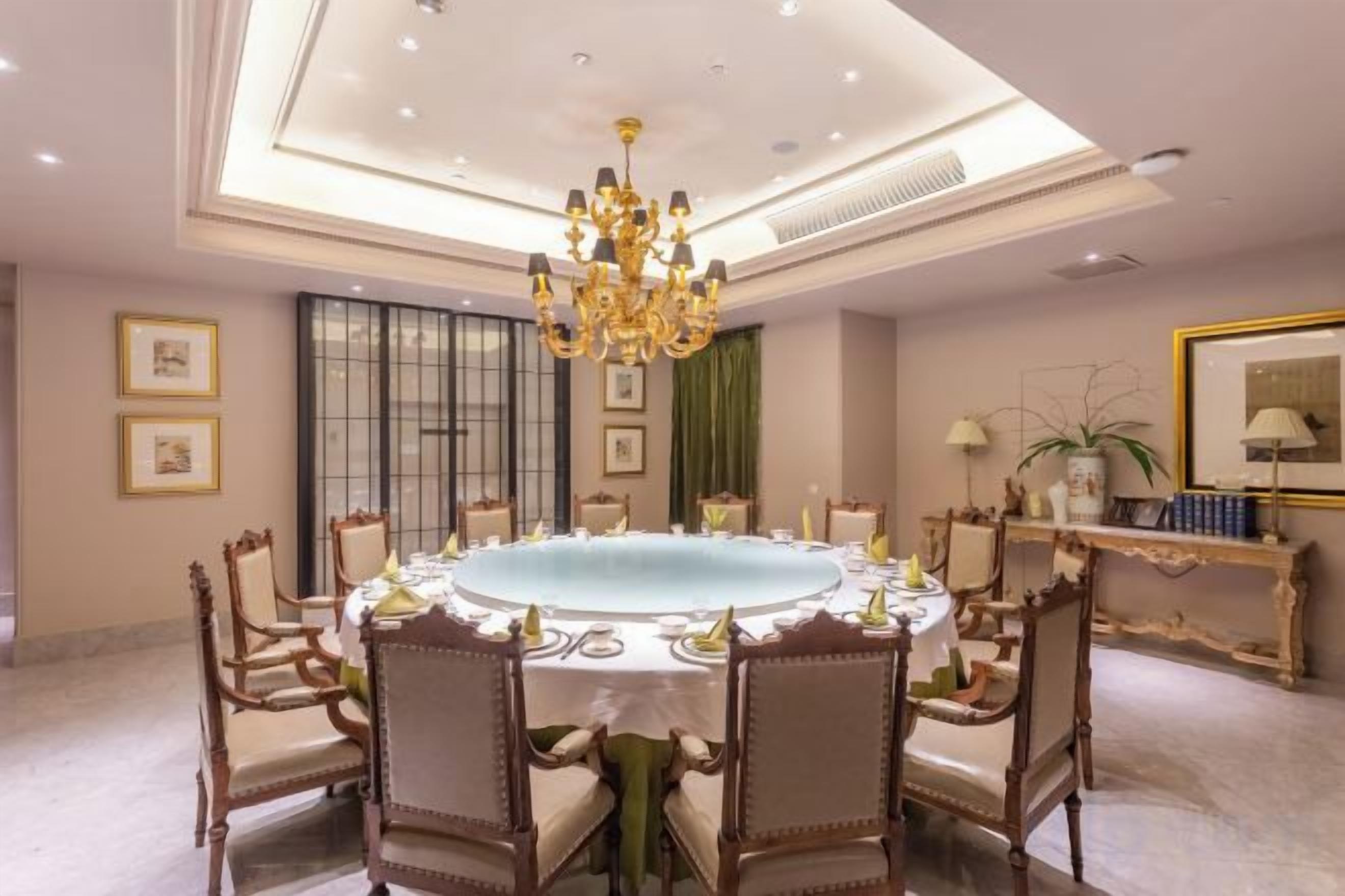 Un comedor formal con una mesa redonda, sillas y una araña.