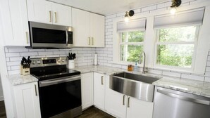 A modern kitchen with white cabinets, a stainless steel sink, a microwave, and an oven.