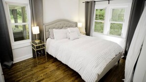 A bedroom with a large bed, two bedside tables, and a window.