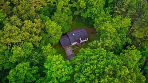 An aerial view of a house surrounded by dense green forest.