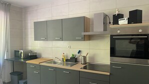 A modern kitchen with grey cabinets, a stainless steel sink, a microwave, a toaster, and an oven. - Vacation apartment "Pingo" Address: Bundesstraße 1, 53506 Ahrbrück!  (Ahrbrück)