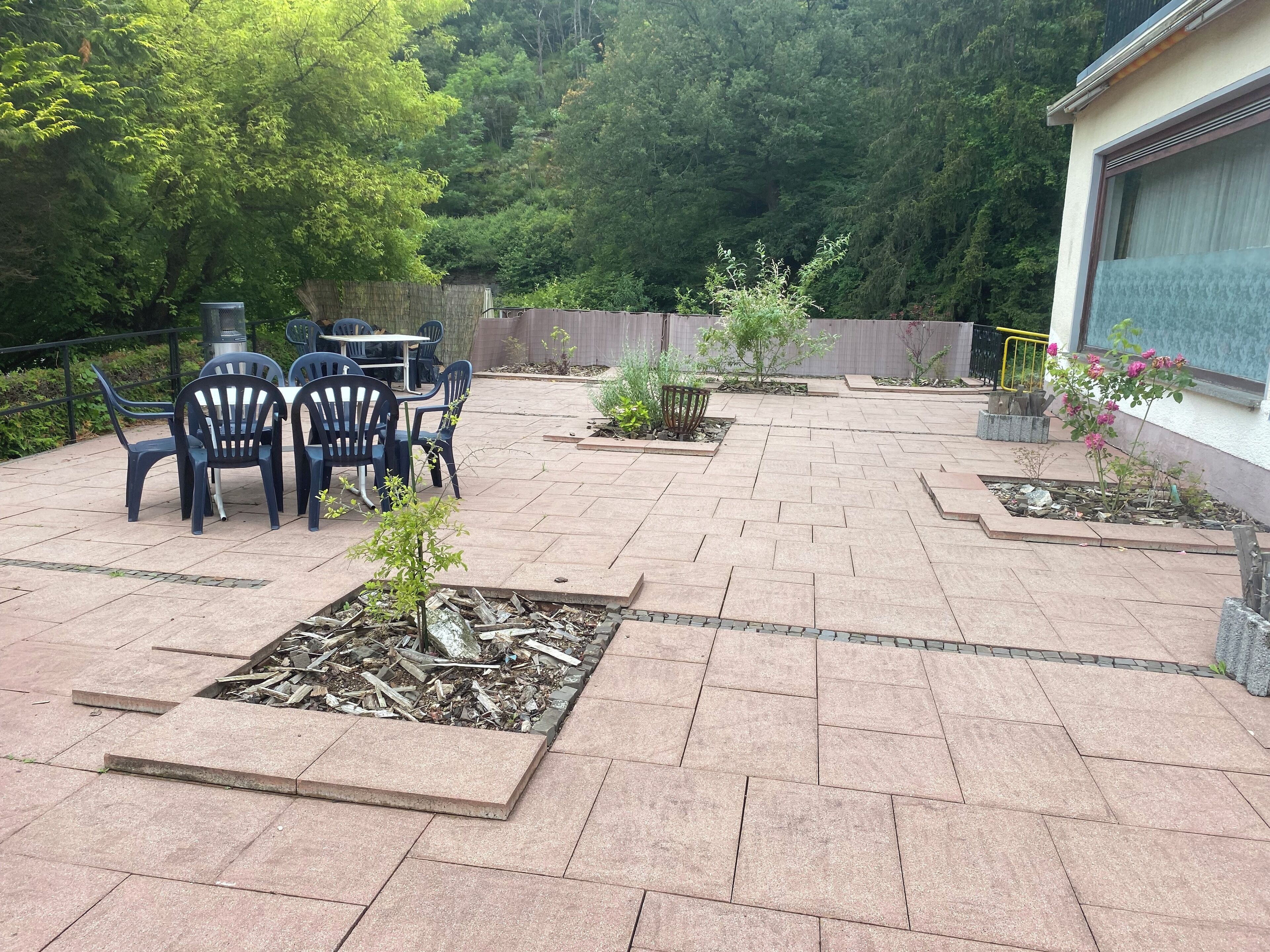 A patio area with a table and chairs, surrounded by planters and a wooden deck.