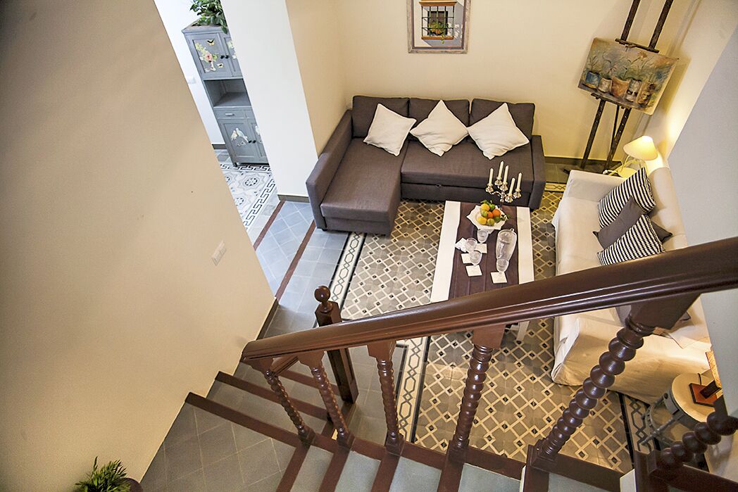 A modern living room with a sofa, coffee table, and a staircase leading to another level.