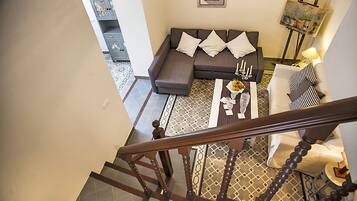 A modern living room with a sofa, coffee table, and a staircase leading to another level.