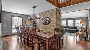 A dining area with a stone accent wall, wooden chairs, and a chandelier.